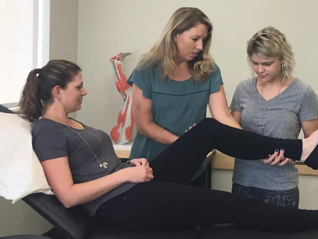 Doctor Tonya Olson of Centaur Physical Therapy demonstrates the proper technique to an intern during a treatment session.